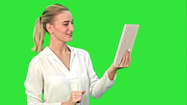 Positive-businesswoman-is-talking-on-the-skype-with-partners-on-tablet-on-a-Green-Screen,-Chroma-Key
