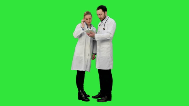 Enfermera-muy-femenina-y-guapo-médico-con-estetoscopio-con-tableta-digital-en-una-pantalla-verde-Chroma-Key