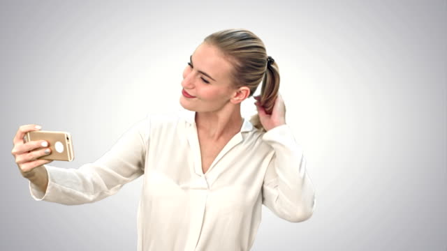 Businesswoman-taking-funny-selfie-with-phone-on-white-background