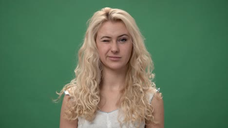 Young-blonde-woman-in-a-white-top-is--winking-and-smiling,-chroma-key-green-screen-background