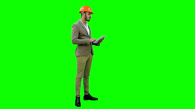 Ingeniero-en-casco,-llevar-a-cabo-inspección-usando-el-tablet-a-una-pantalla-verde-Chroma-Key
