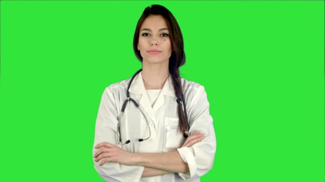 Atractivo-joven-mujer-doctor-en-bata-blanca-con-estetoscopio-mirando-a-la-cámara-en-una-pantalla-verde-Chroma-Key