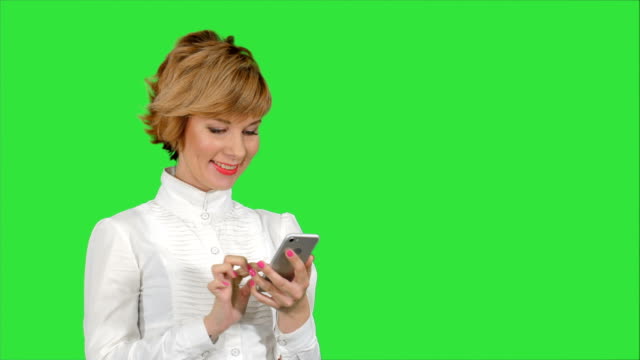 Junge-attraktive-Frau-arbeitet-an-Smartphone-und-ein-Lächeln-auf-einem-Green-Screen,-Chroma-Key