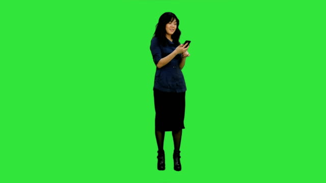 Schöne-Asiatin-mit-Smartphone-singen-und-tanzen-beim-Musikhören-auf-einem-Green-Screen,-Chroma-Key