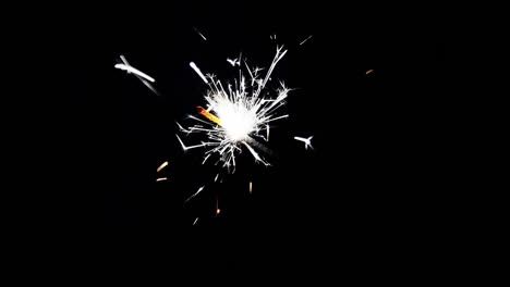 Close-up-burning-of-Christmas-sparkler.-Firework-lit-on-black-background.