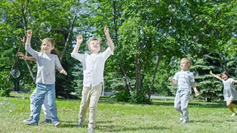 Glückliche-Kinder-jagen-Seifenblasen-auf-Outdoor-Party