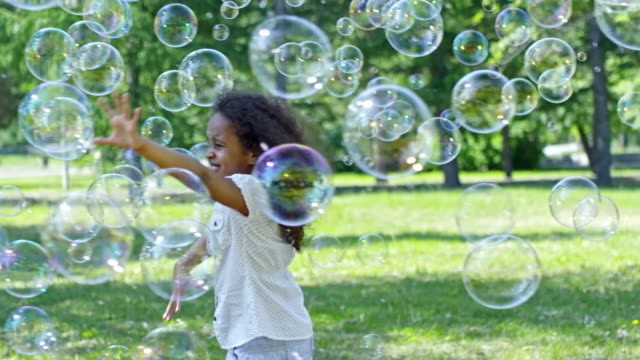 Niña-y-muchacho-cogiendo-las-burbujas-de-jabón-al-mismo-tiempo-jugando-al-aire-libre