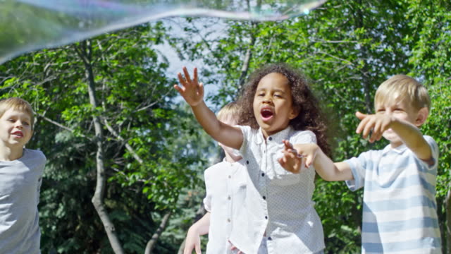 Begeistert-kleine-Kinder-tauchen-riesige-Seifenblase