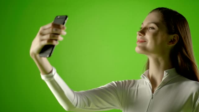 Attraktives-Mädchen-junge-Mode-Modell-Interract-mit-ihrem-Smartphone-und-nehmen-Selfie-Greenscreen-schieße-Prores-auf-Ursa-Mini-pro