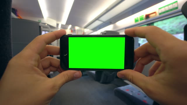 Manos-sosteniendo-un-teléfono-con-una-pantalla-verde-en-el-tren