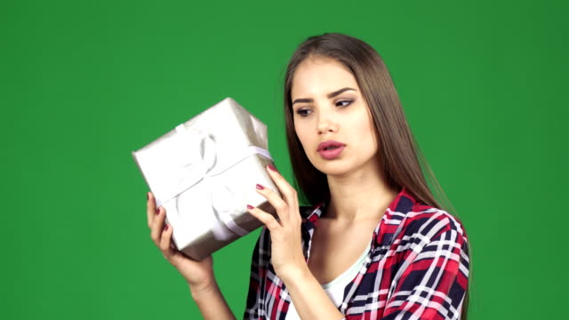 Stunning-happy-young-woman-shaking-present-box-guessing-what-is-inside