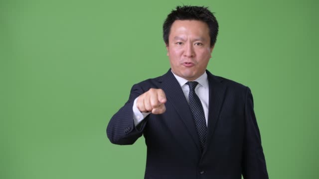Reife-japanischer-Geschäftsmann-vor-grünem-Hintergrund