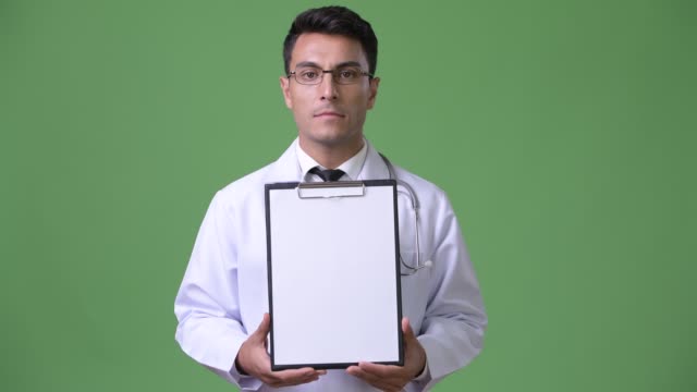 Junge-hübsche-Hispanic-Mann-Arzt-vor-grünem-Hintergrund