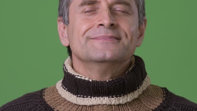 Mature-handsome-man-wearing-turtleneck-sweater-against-green-background