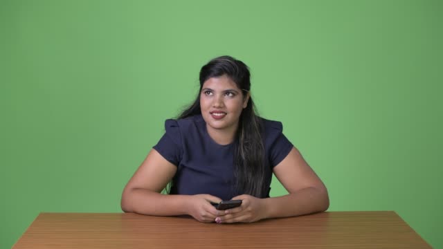 Junge-übergewichtige-schöne-indische-geschäftsfrau-vor-grünem-Hintergrund