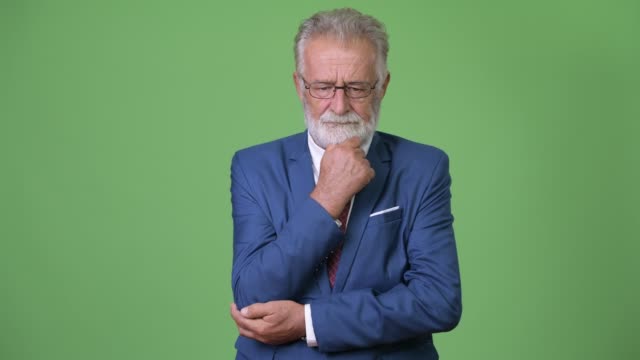 Handsome-senior-bearded-businessman-against-green-background