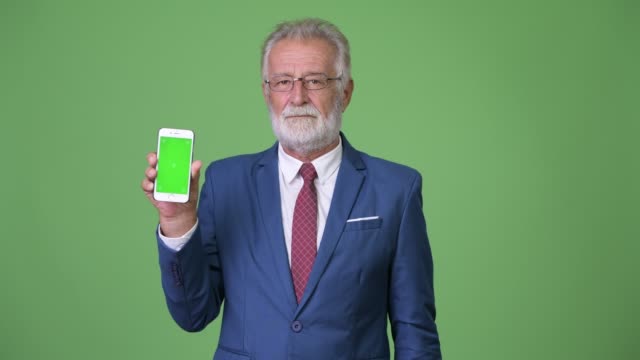 Gut-aussehend-senior-bärtigen-Geschäftsmann-vor-grünem-Hintergrund