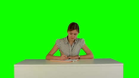 Young-girl-sitting-in-classroom-at-lecture-and-listening-teacher-on-a-Green-Screen