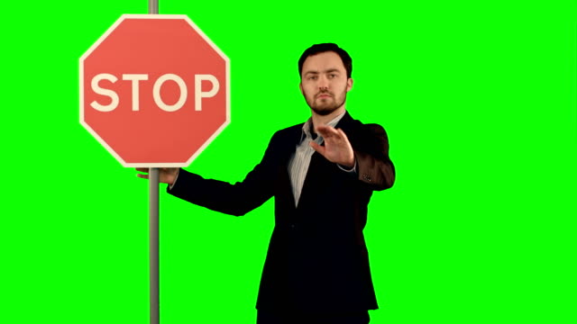 A-businessman-holding-a-stop-sign-on-laptop-on-a-Green-Screen,-Chroma-Key