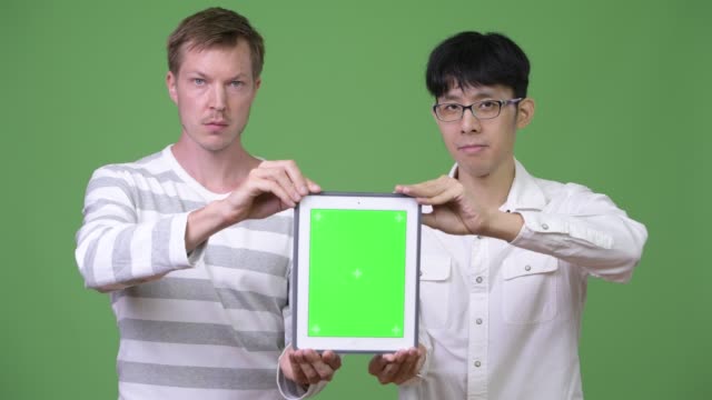Dos-jóvenes-empresarios-multiétnicos-mostrando-tableta-digital-de-la-cámara-juntos