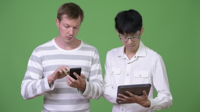 Zwei-multi-ethnischen-Jungunternehmer-mit-Telefon-und-digital-Tablette-für-social-Media-Konzept
