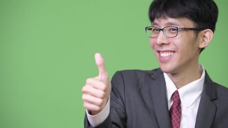 Young-happy-Asian-businessman-smiling-while-giving-thumbs-up