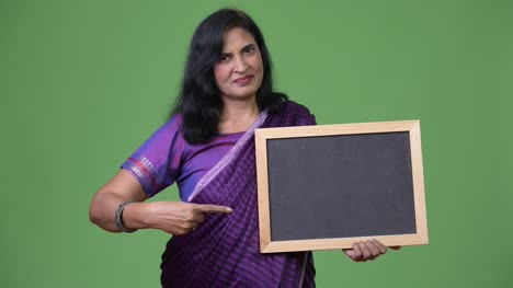 Mature-beautiful-Indian-woman-pointing-to-blackboard