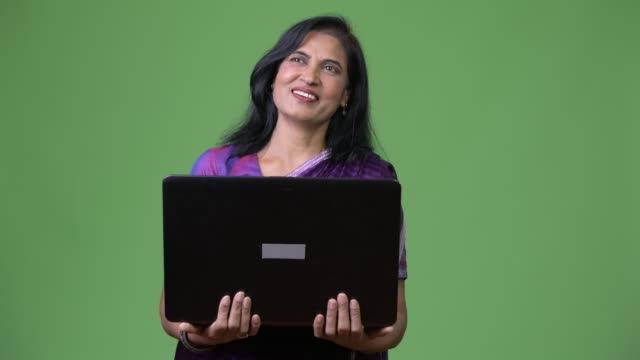 Mature-happy-beautiful-Indian-woman-thinking-while-laptop
