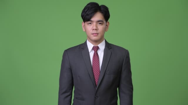 Junge-hübsche-asiatische-Geschäftsmann-vor-grünem-Hintergrund