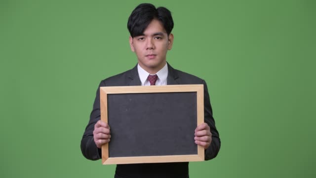 Junge-hübsche-asiatische-Geschäftsmann-zeigt-Tafel