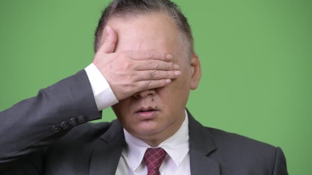 Mature-Japanese-businessman-covering-eyes-as-three-wise-monkeys-concept