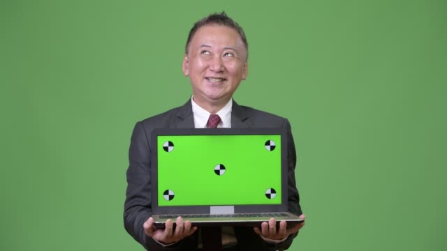 Mature-Japanese-businessman-showing-laptop