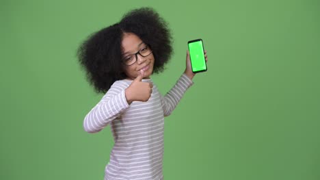 Junge-süße-Afrikanische-Mädchen-mit-Afro-Haar-zeigt-Handy-und-Daumen-aufgeben