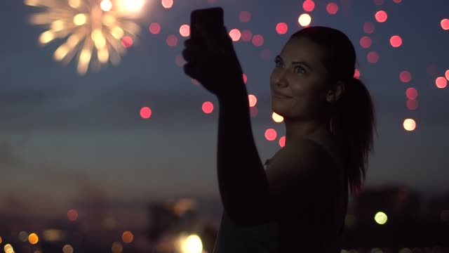 Eine-Mädchen-verwendet-eine-Sartphone,-während-ein-Feuerwerk.-4K