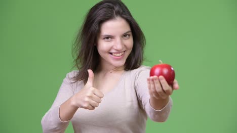 Mujer-hermosa-joven-manteniendo-apple-y-dar-pulgares-para-arriba