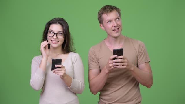 Young-happy-couple-using-phone-and-thinking-together