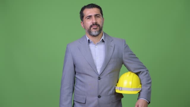 Gut-aussehend-glücklich-persischen-bärtigen-Geschäftsmann-als-Ingenieur-lächelnd