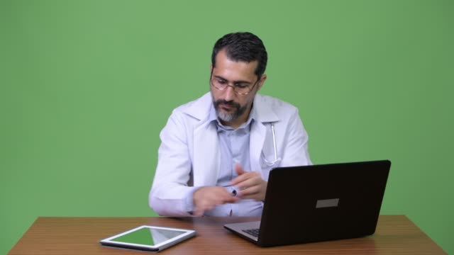 Gut-aussehend-persischen-bärtigen-Mann-Arzt-Multitasking-bei-der-Arbeit