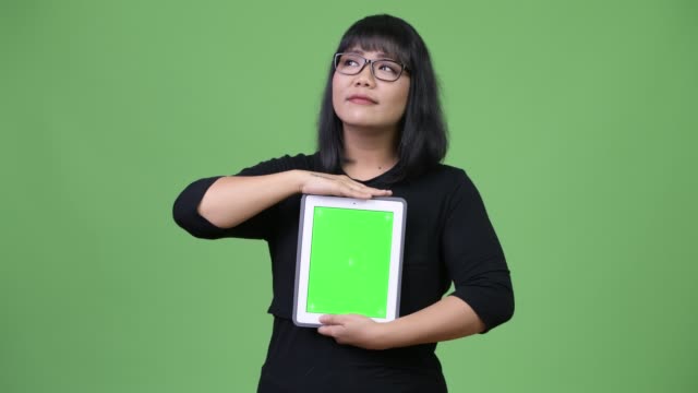 Pensamiento-y-bella-empresaria-asiática-mostrando-tableta-digital