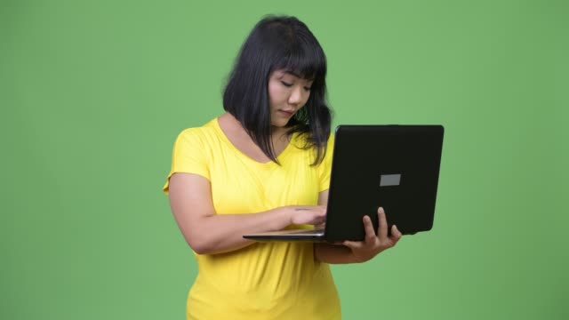 Schöne-asiatische-Frau-denken-während-mit-laptop