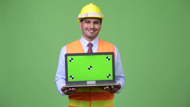 Trabajador-de-la-construcción-del-joven-persa-guapo-mostrando-portátil