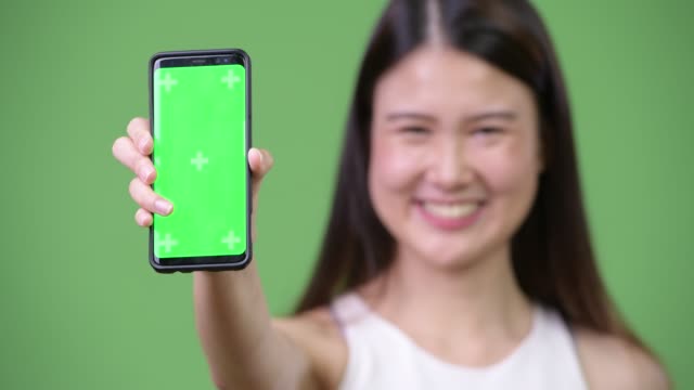 Young-beautiful-Asian-businesswoman-showing-phone