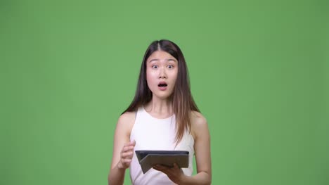 Young-beautiful-Asian-businesswoman-using-digital-tablet
