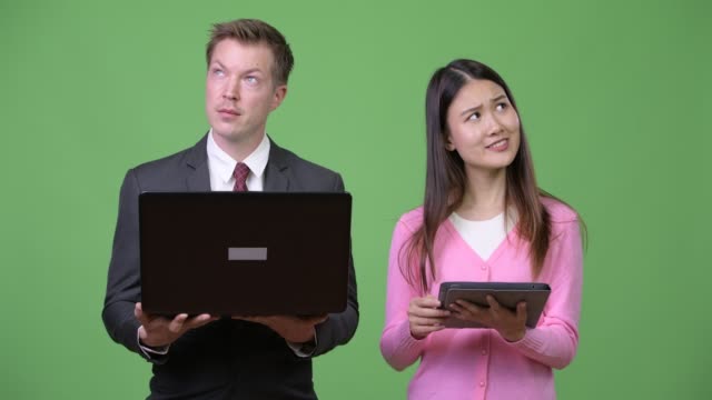 Young-Asian-woman-and-young-businessman-using-laptop-and-digital-tablet-together
