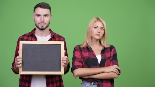 Young-couple-holding-blackboard-and-arms-crossed-together