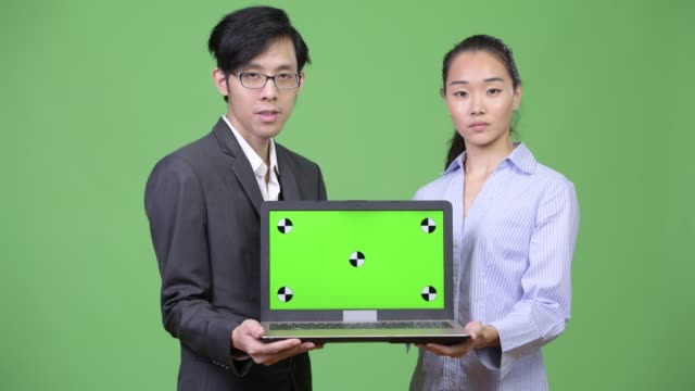 Young-Asian-business-couple-showing-laptop-together
