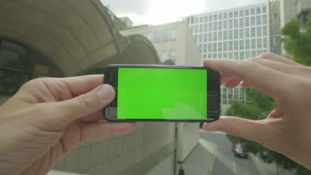Personal-perspective-of-a-man-using-a-Green-Screen-smartphone-outside-the-office