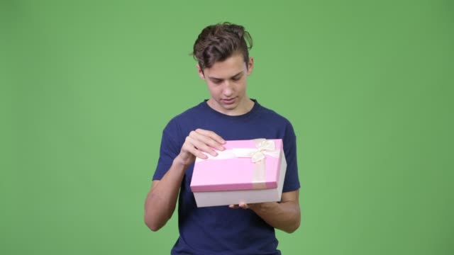 Young-handsome-teenage-boy-opening-gift-box