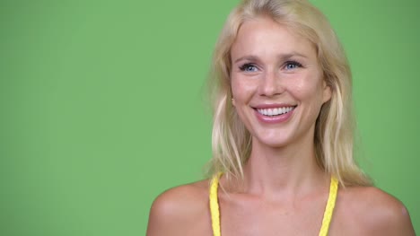 Junge-glücklich-schöne-blonde-Frau-vor-grünem-Hintergrund-denken