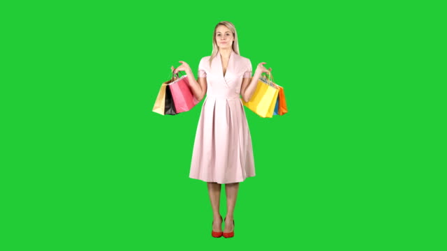 Woman-with-shopping-bags-in-pink-dress-standing-on-a-Green-Screen,-Chroma-Key